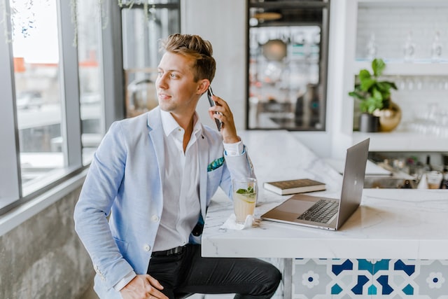 man sitting near white table and calling by phone